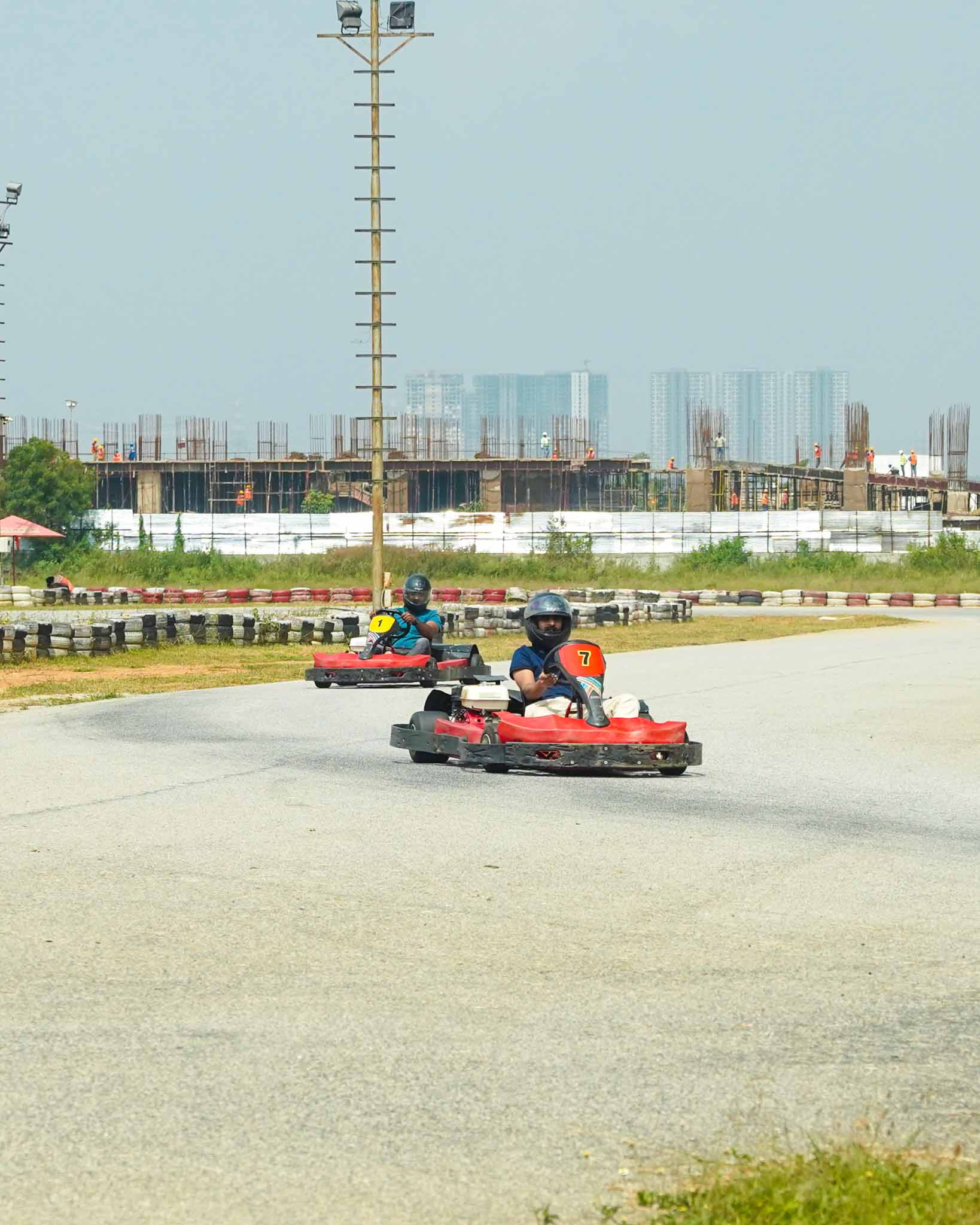 Two go-karts racing on a track, with construction in the background.